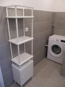 a laundry room with a washing machine and white shelves at Eschenkamp 7a in Isenbüttel