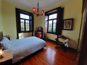 a bedroom with a bed and wooden floors and windows at B&B Casa das Eiras in Pereira