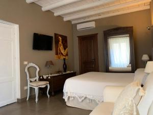 a bedroom with a bed and a chair and a tv at B&B Mugnos Charme Living in Licodia Eubea