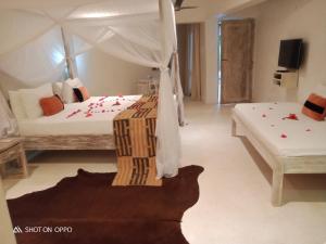 1 Schlafzimmer mit 2 Betten und einem Himmelbett in der Unterkunft The Villa Luxury Suites Hotel in Diani Beach