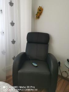 a black reclining chair with a remote control on it at Mama Teasa-Apartment in Curtea de Argeş