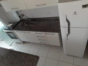 a white kitchen with a sink and a refrigerator at Apto 2 dormitórios à 400 m da Praia de Riviera de São Lourenço - com serviço de praia in Bertioga