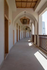einem leeren Korridor eines Gebäudes mit Torbogen in der Unterkunft Liwa Hotel in Mezairaa