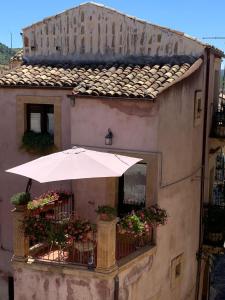 een gebouw met een paraplu en bloemen op een balkon bij B&B Mugnos Charme Living in Licodia Eubea