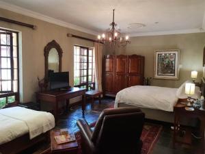 a bedroom with two beds and a desk and a chair at The Lemon Tree Self- Catering in Johannesburg