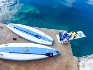 two surfboards sitting on a ledge next to the water at Sound Winds private oceanfront estate with private tennis court & swim dock Property overview in Harrington Hundreds