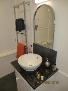 y baño con lavabo blanco y espejo. en Pengelly - Luxury converted Fisherman’s Net Loft, en Mousehole