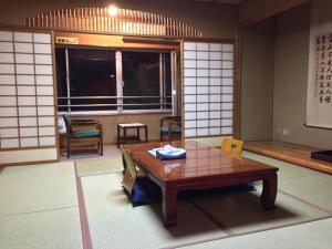 a room with a table and chairs and a window at Iwamuro Slow Hostel in Niigata