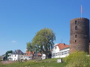 an old tower and a white house and a tree at Ferienhaus Wallstraße in Rees