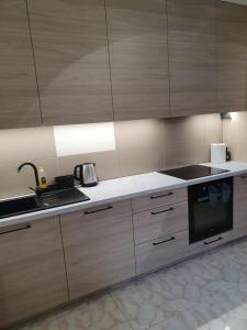 a kitchen with wooden cabinets and a sink and a stove at Szmaragdowy Apartament in Szczawnica