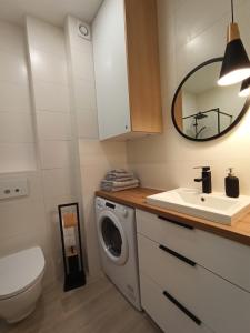 a bathroom with a washing machine and a sink at Apartament Września II in Września