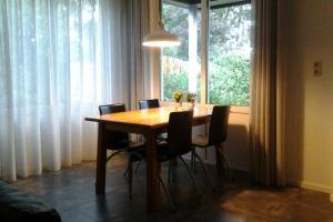 a dining room table with chairs and a large window at Vakantiehuisje Gaasterland Oudemirdum Friesland Nederland in Oudemirdum