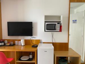 um quarto com uma secretária, um micro-ondas e um frigorífico em Apart suite frente ao mar no Rio de Janeiro