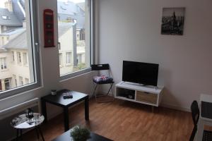 a living room with a flat screen tv and a window at HYPER CENTRE - WIFI FIBRE GRATUIT - JERGWELOH - Le Londonien in Caen