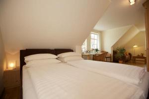 una camera da letto con un letto bianco con lenzuola e cuscini bianchi di Schimmels Pension a Wustrow