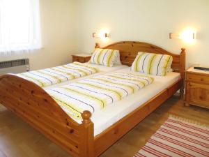 a large wooden bed with white sheets and pillows at Apartments Roemerschlucht in Velden am Wörthersee