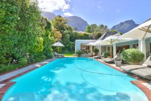 a swimming pool in a backyard with mountains in the background at Fernwood Manor Boutique Guest House in Cape Town
