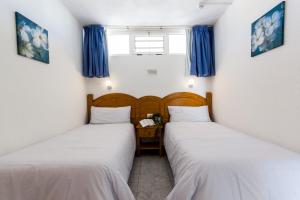 Dos camas en una habitación con cortinas azules. en Seaview Friendly Holiday Home 1, en Playa del Inglés