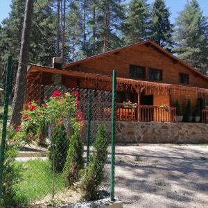 ein Blockhaus mit einem Zaun davor in der Unterkunft Къща за гости ЕКО in Tsigov Chark