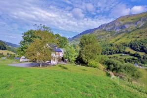 a house in a field with mountains in the background at Le Carot : gîte de montagne indépendant et calme in Campan