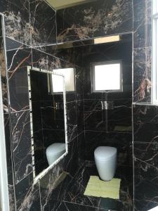 a black marble bathroom with two toilets and a window at Somerset Inn in Durban