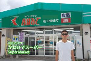 宜野湾市にあるTs squareのスーパーの前に立つ男