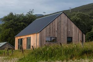 a wooden barn with a black roof in a field at Beautiful views from right above the water in Dunan