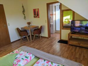 a living room with a television and a table with chairs at Haus am Grasberg in Poppenhausen