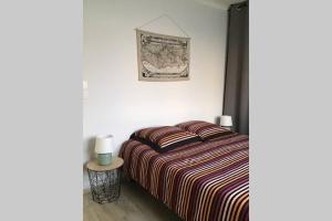 1 dormitorio con 1 cama con manta a rayas y mesa en Charmante Maison idéalement située, en Saint Gilles Croix de vie