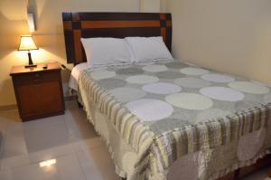1 dormitorio con 1 cama y mesita de noche con lámpara en Rosenverg House Lima Airport, en Lima
