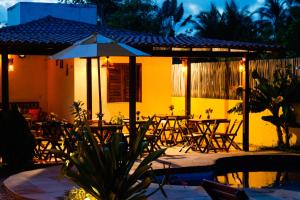 a patio with tables and chairs and an umbrella at Pousada Icaraizinho Praia in Icaraí