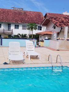 zwei Stühle und ein Pool vor einem Haus in der Unterkunft Apto Aconchegante Enseada Azul com Wi-Fi in Guarapari