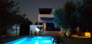a swimming pool in front of a house at night at Villa Marcyr in Kamilari
