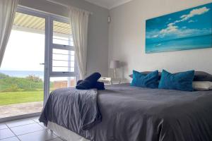 a bedroom with a large bed with a large window at Tamassa Holiday Home on the Beach, in Port Edward in Port Edward
