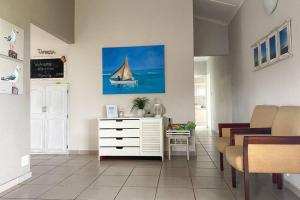 a living room with a white dresser and a sail boat on the wall at Tamassa Holiday Home on the Beach, in Port Edward in Port Edward
