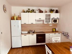 La cuisine est équipée de placards blancs et d'un réfrigérateur blanc. dans l'établissement Apartmán pod Božím Darem, à Jáchymov