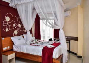 Schlafzimmer mit einem Bett mit roten Vorhängen und einem Fenster in der Unterkunft Divine Homes Resort Kisumu in Kisumu