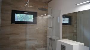a bathroom with a shower with a sink and a mirror at Vega Apartamenty in Pobierowo