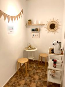 a kitchen with two stools and a table and a shelf at Pensi&oacute;n La Cantarera in C&aacute;diz