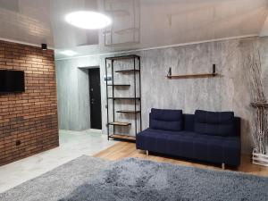 a living room with a blue couch and a brick wall at ВИТАЛИЯ МАТУСЕВИЧА ДОМ 4 in Kryvyi Rih