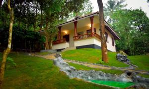 a house in the middle of a grassy yard at Green Garden Holiday Home Wayanad in Vythiri