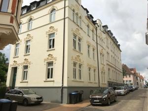 ein weißes Gebäude mit davor geparkten Autos in der Unterkunft Apartment am Schelfmarkt in Schwerin