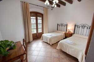 1 dormitorio con 2 camas, mesa y ventana en Hostal El Cortijo, en Algodonales