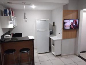 a kitchen with a refrigerator and a tv on the wall at Parque ALDEIA DAS ÁGUAS Village flat in Barra do Piraí