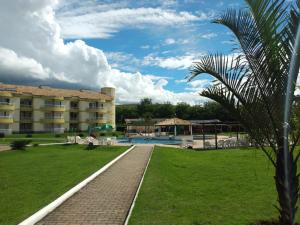 a resort with a swimming pool and a palm tree at Parque ALDEIA DAS ÁGUAS Village flat in Barra do Piraí