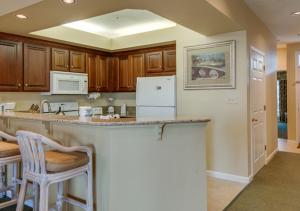 Una cocina con gabinetes de madera y un mostrador con taburetes. en Ocean Palms Villa with Championship Golf Saturday to Saturday Rental, en Hilton Head Island