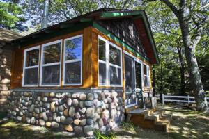 a log cabin with windows and a rock wall at Main Cabin - STARRY NIGHTS cabin in Carp Lake