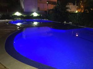 uma piscina azul à noite com luzes em Laguna Beach Flat em Porto de Galinhas