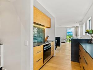 a kitchen with white walls and wooden cabinets at Stay Soudley @ Jack's in Frankton Wharf