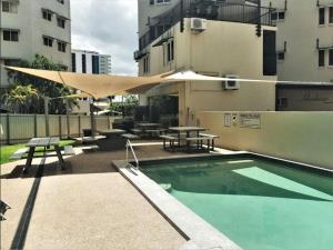 a swimming pool with a picnic table and a umbrella at Inner city Cardona Court apartment in Darwin